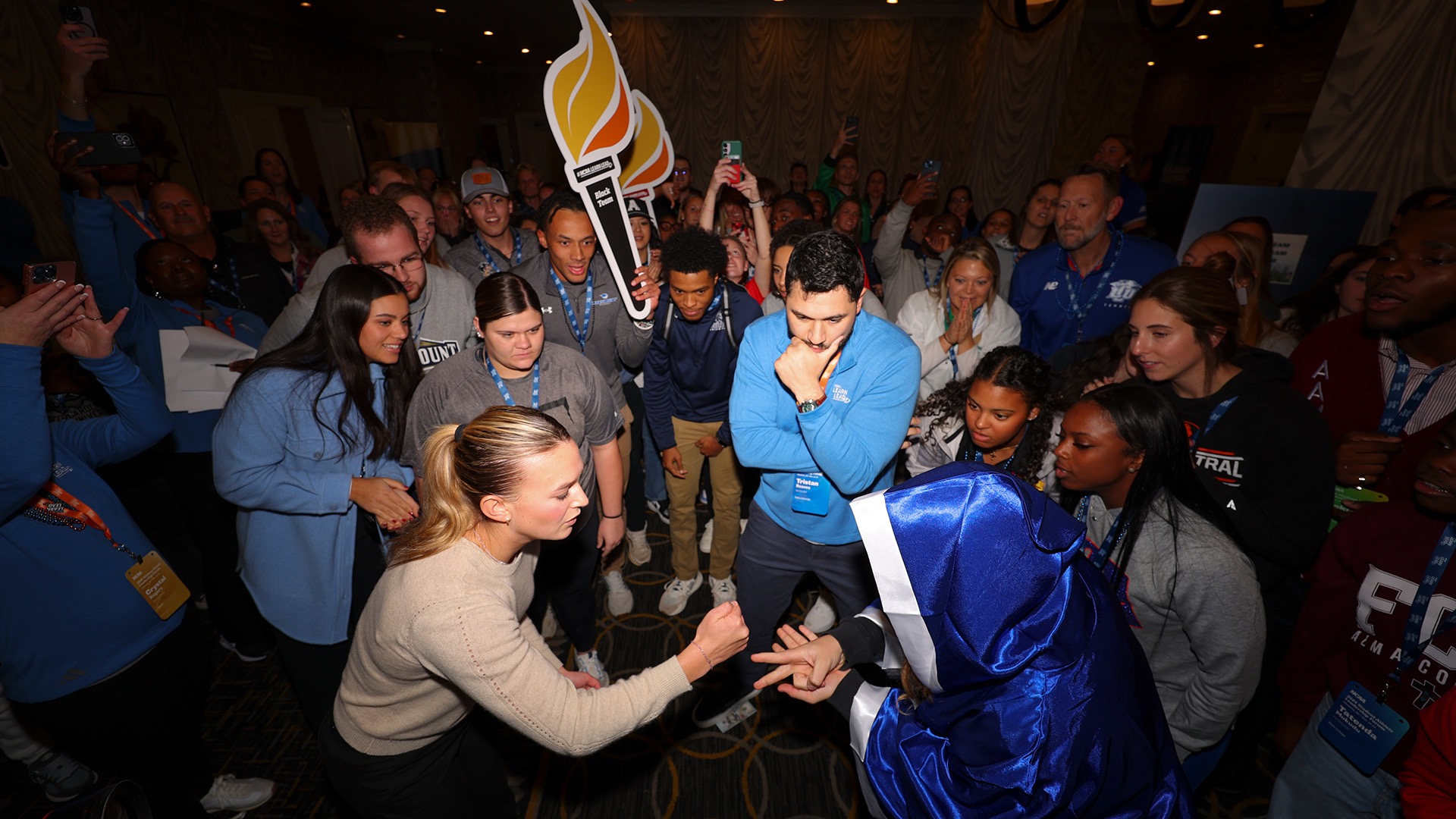 Two participants square off in rock, paper, scissors as over 200 people cheer them on.