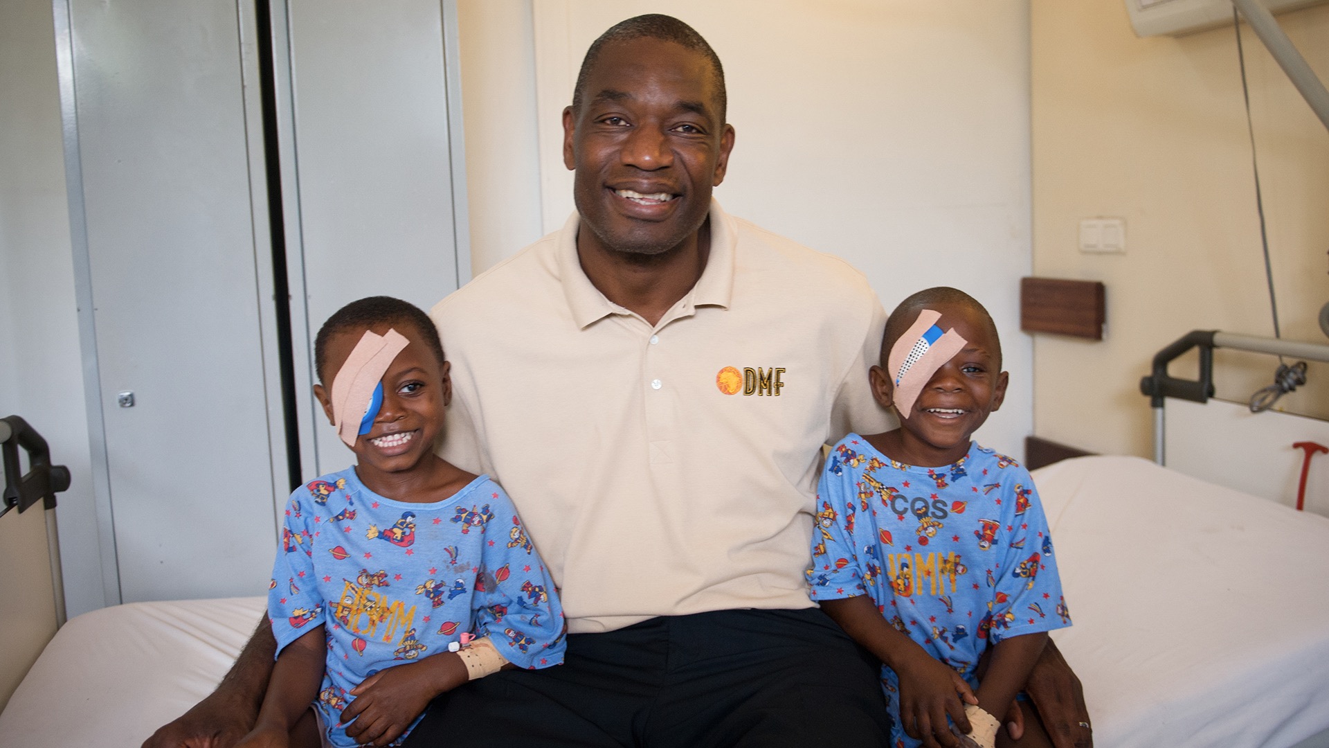 Mutombo sits with two young patients inside the Biamba Marie Mutombo Hospital, named for his mother. (Photo courtesy of the Dikembe Mutombo Foundation)