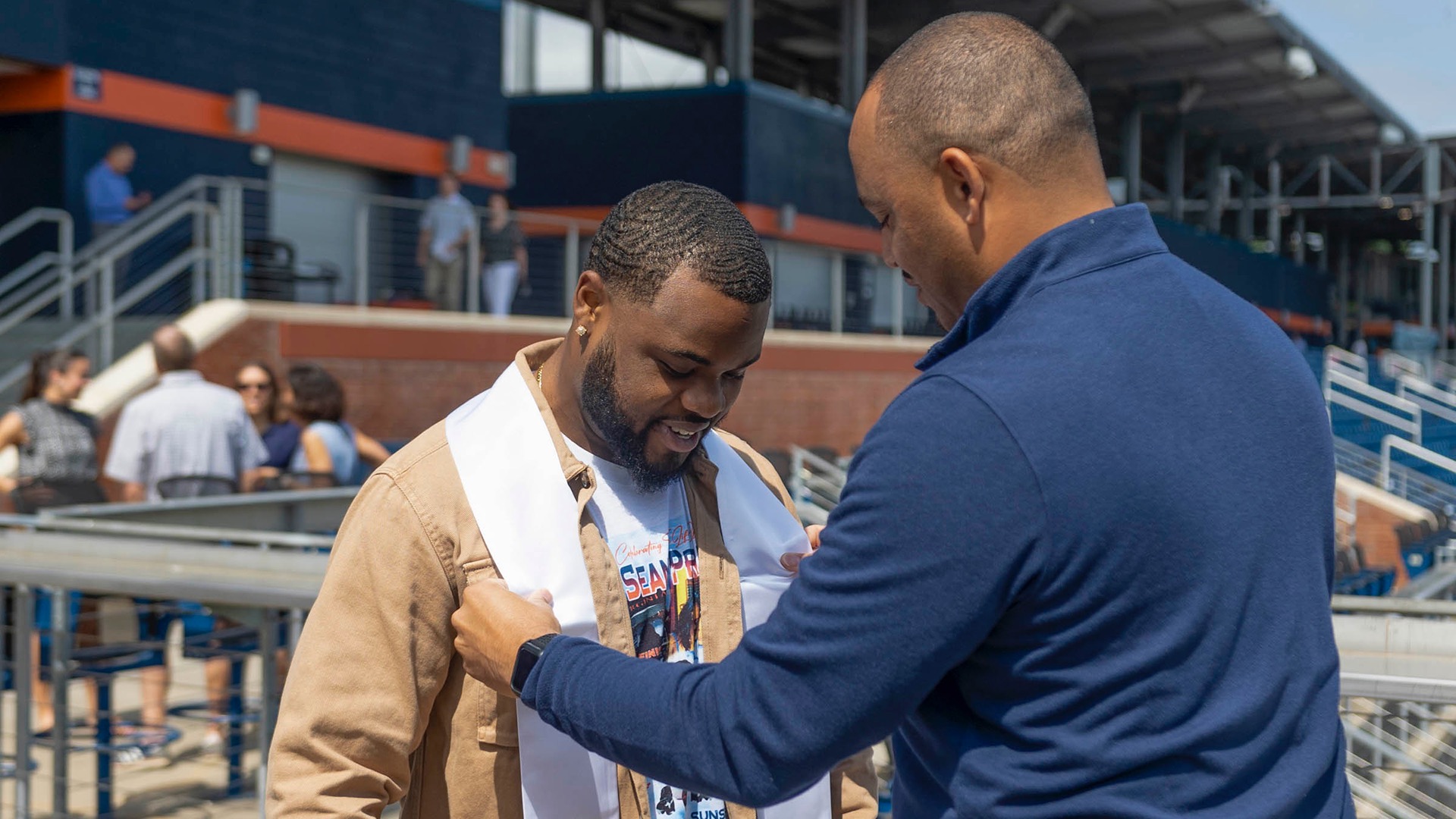 Virginia head football coach Tony Elliott places a graduation stole on Hollins. (Photo courtesy of Virginia)