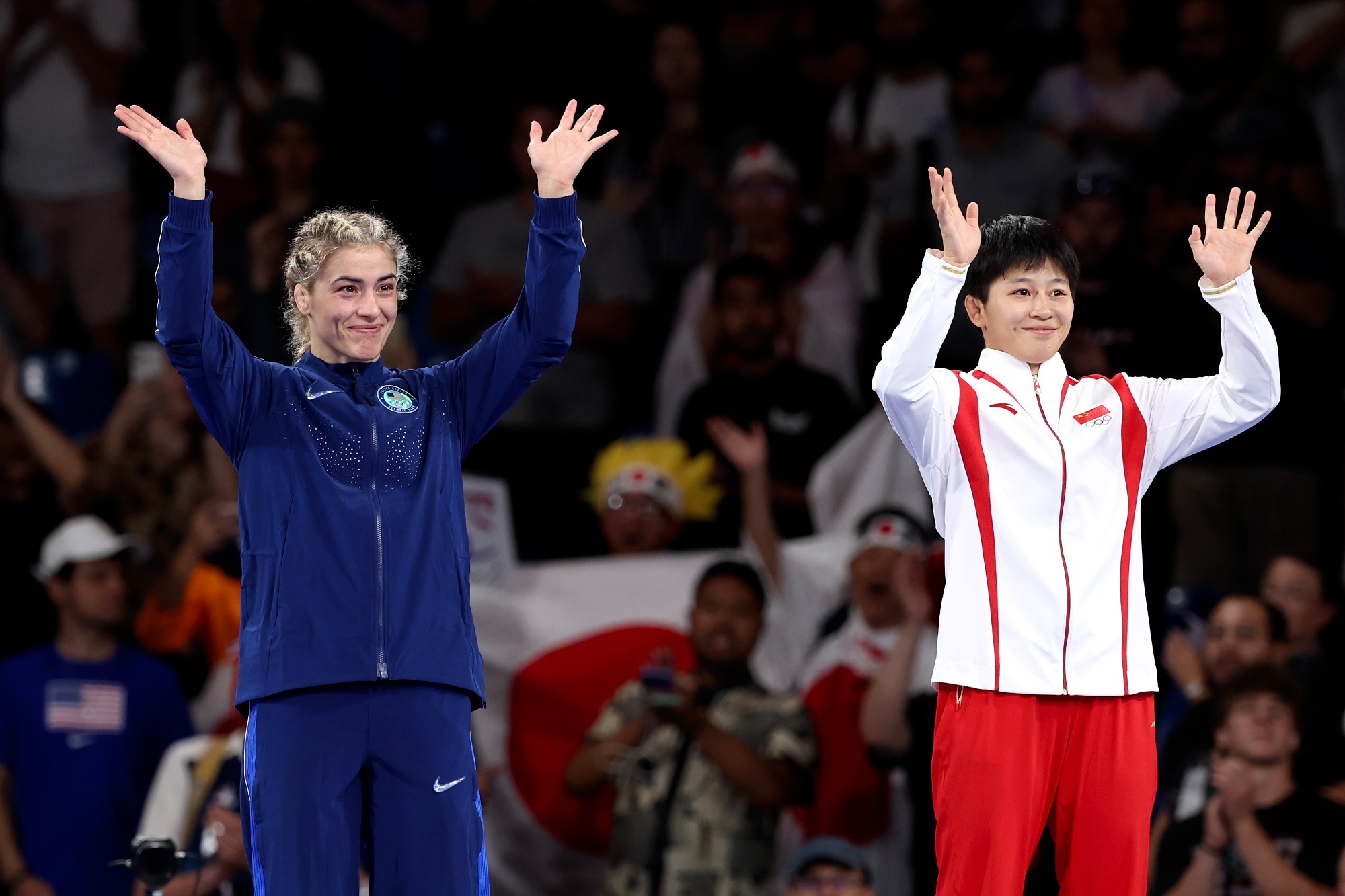 PARIS, FRANCE - AUGUST 09: Bronze medallists Helen Louise Maroulis of Team United States and Kexin Hong of Team People's Republic of China acknowledge the crowd on the podium during the Wrestling Women's Freestyle 57kg medal ceremony after the Wrestling Women's Freestyle 57kg matches on day fourteen of the Olympic Games Paris 2024 at Champs-de-Mars Arena on August 09, 2024 in Paris, France. (Photo by Julian Finney/Getty Images)